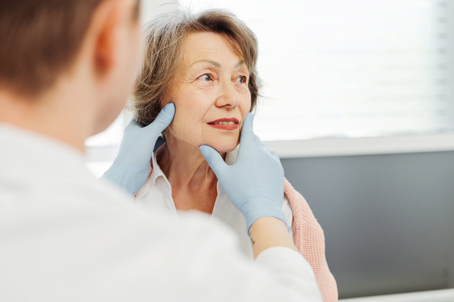 Attractive senior woman, patient talking to cosmetologist doctor, he touches her face, lifting, botox, rejuvenation. Skin care concept, cosmetic procedure